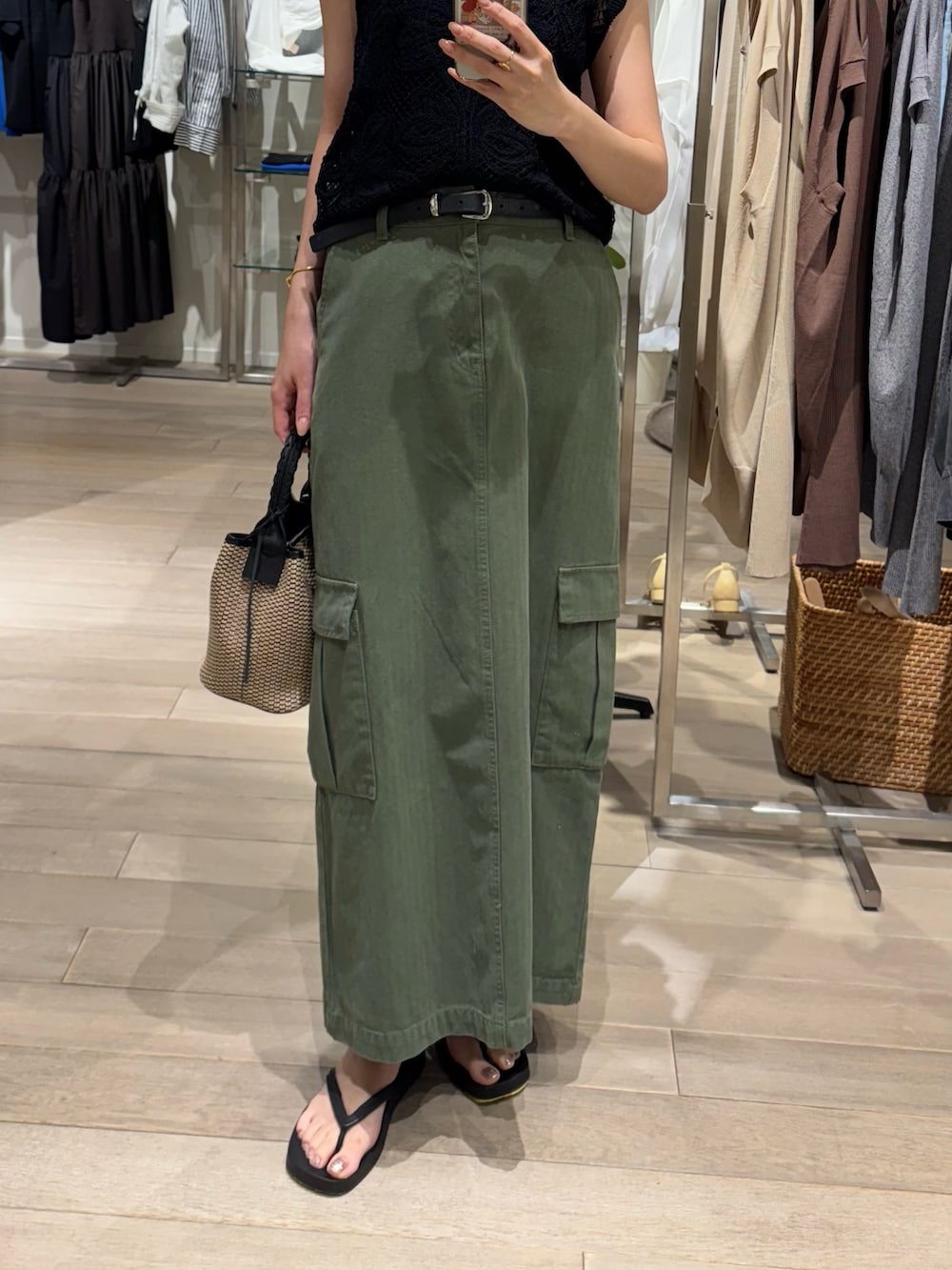 グリーン系のスカート、ブラック系のニット/セーター、ブラック系のキャミソールを着用したレディースの夏コーディネートの3枚目の写真