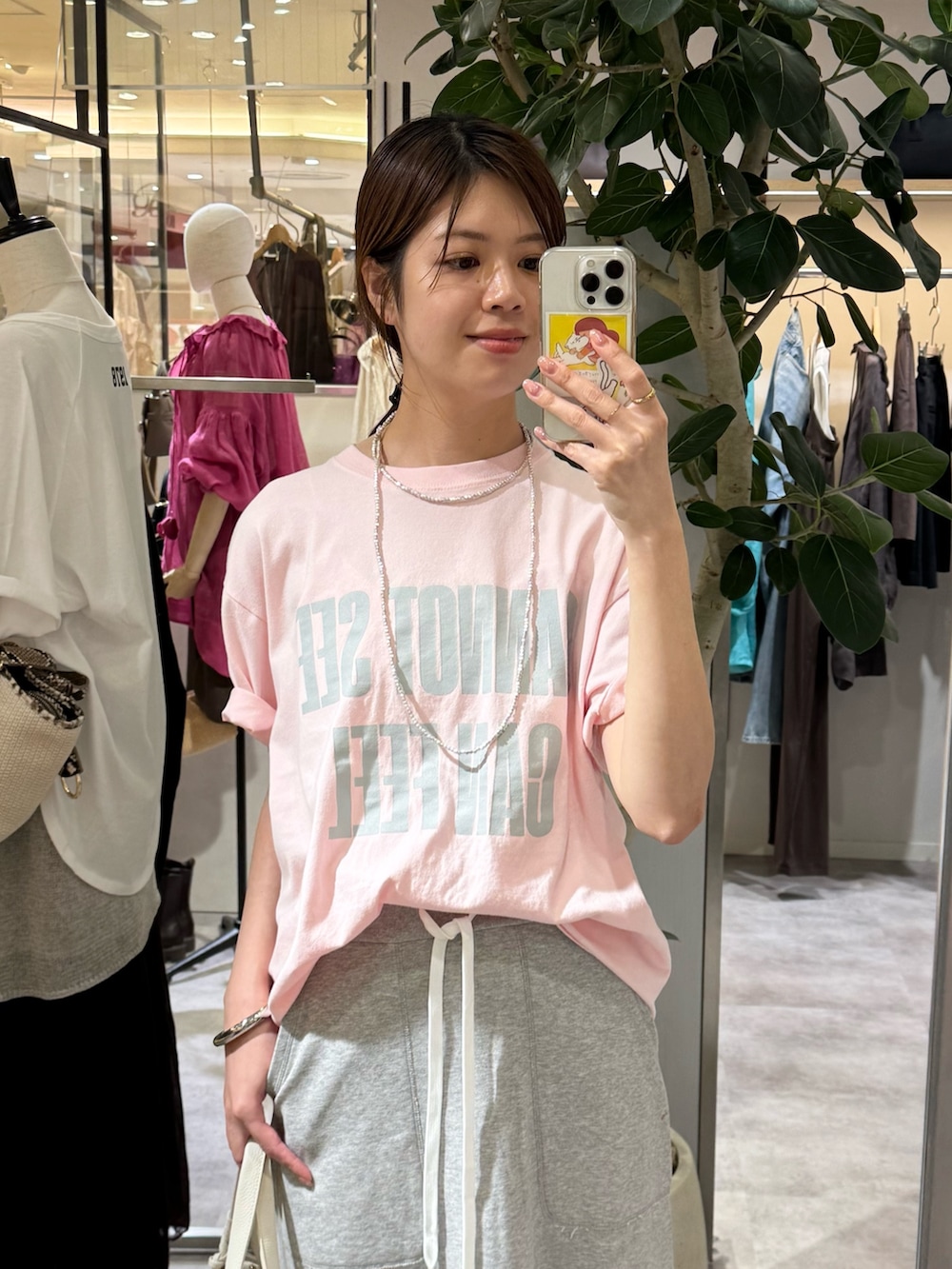 グレー系のスカート、ピンク系のTシャツ/カットソー、ホワイト系のハンドバッグを着用したレディースの夏コーディネートの2枚目の写真