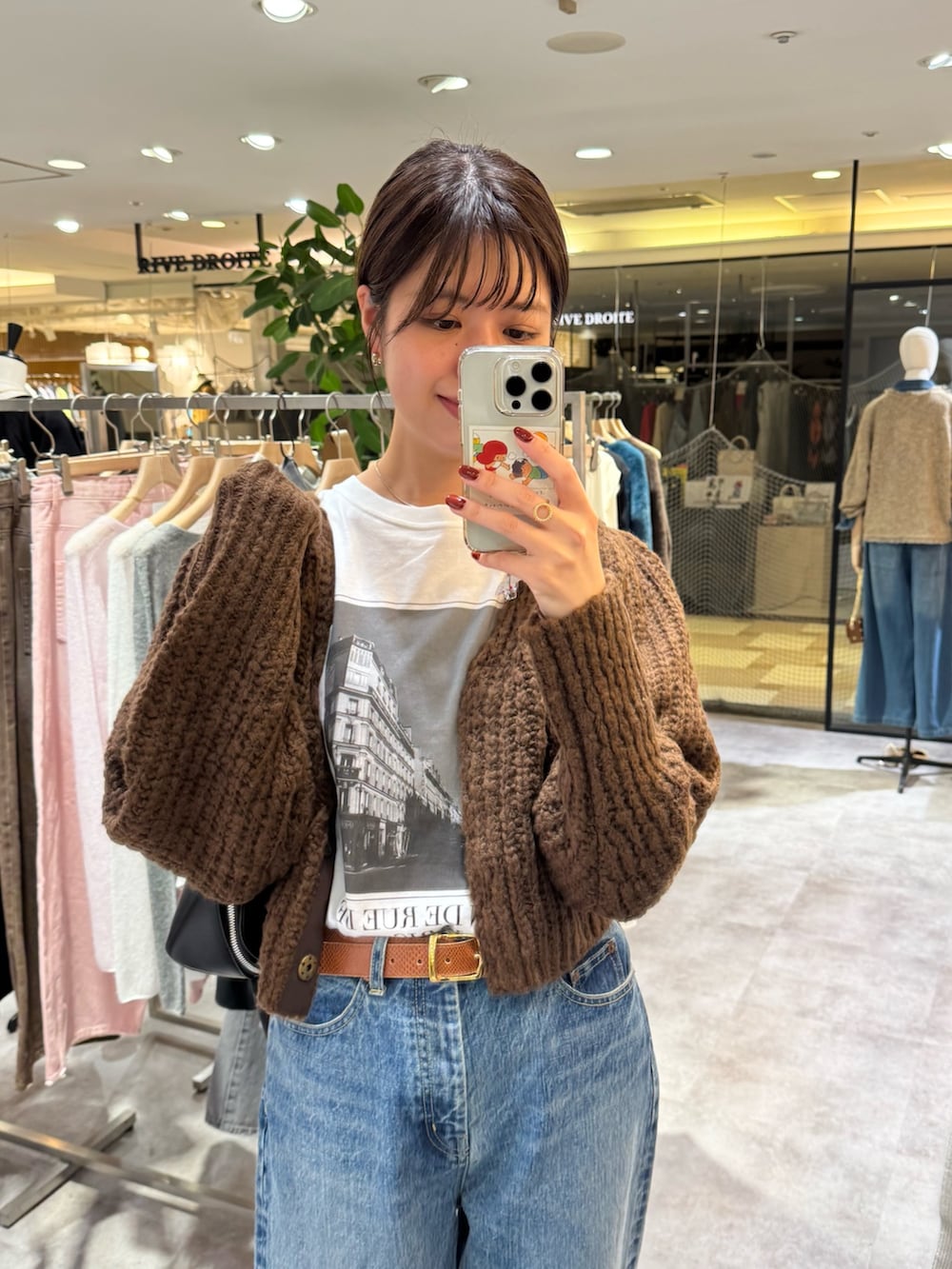 ブラウン系のカーディガン/ボレロ、ホワイト系のTシャツ/カットソー、ブルー系のデニムパンツを着用したレディースの秋コーディネートの2枚目の写真