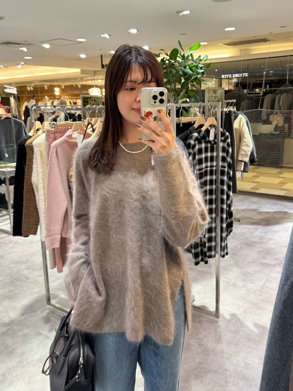ブラウン系のニット/セーター、ブルー系のデニムパンツ、ブラック系のボストンバッグを着用したレディースの秋コーディネートの2枚目の写真