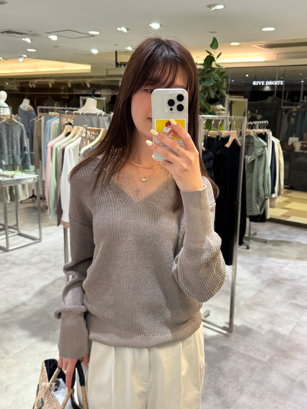 ブラウン系のニット/セーター、ホワイト系のチノパンツを着用したレディースの春コーディネートの2枚目の写真