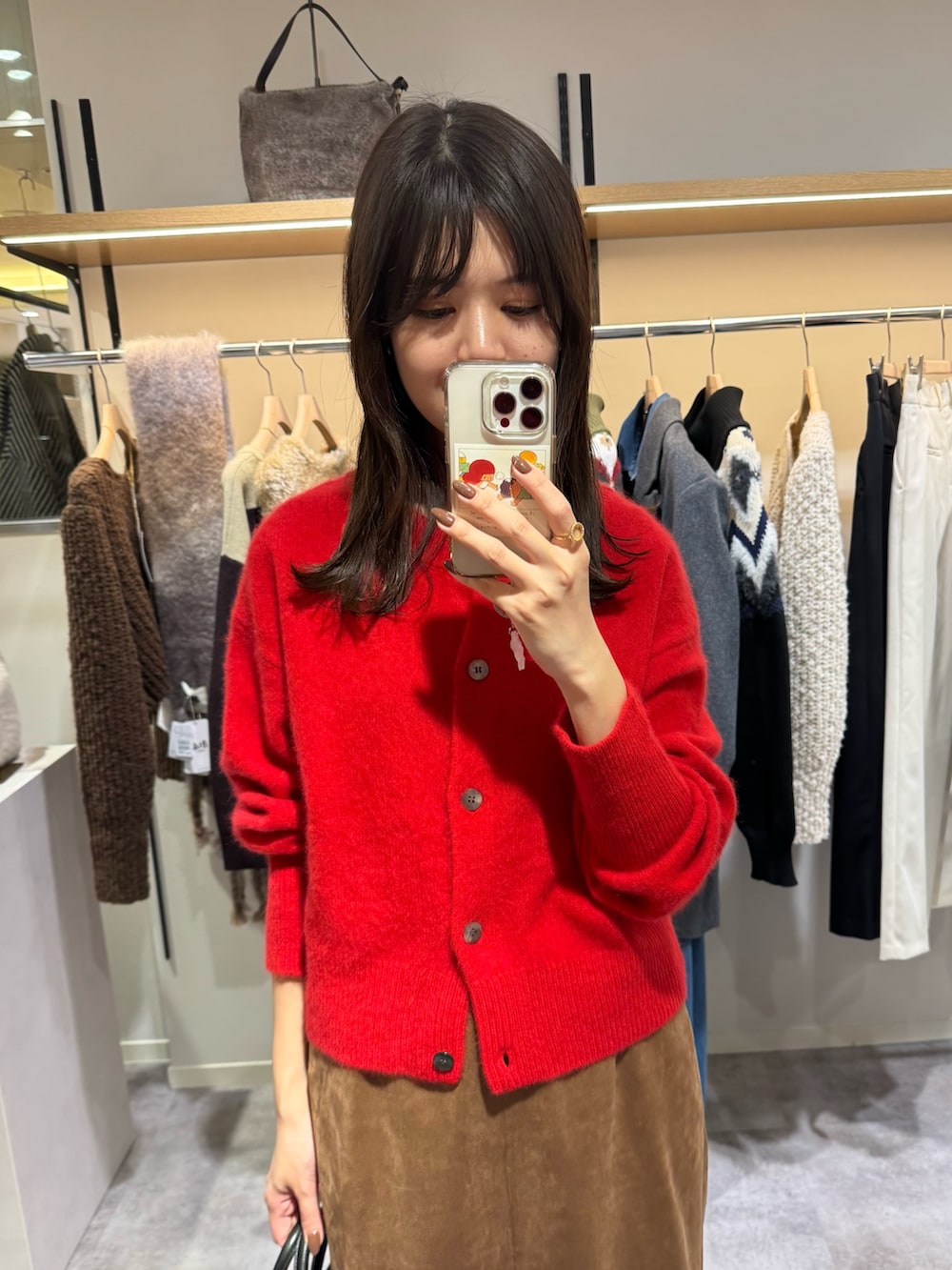 レッド系のカーディガン/ボレロ、ブラウン系のスカート、ブラック系のブーツを着用したレディースの秋コーディネートの2枚目の写真