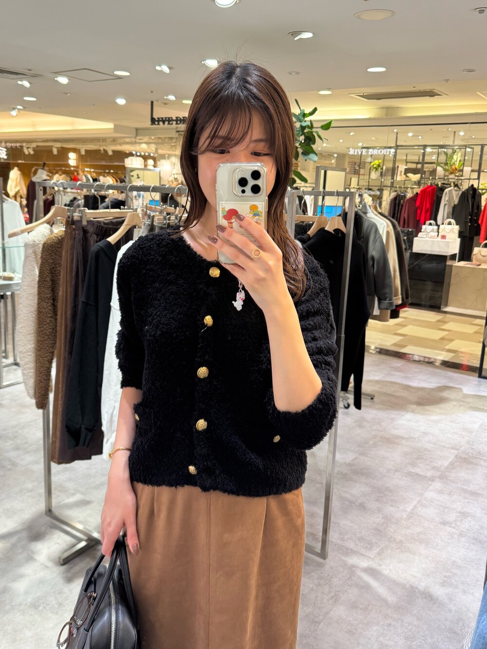 ブラウン系のスカート、ブラック系のブーツ、ブラック系のカーディガン/ボレロを着用したレディースの秋コーディネートの2枚目の写真