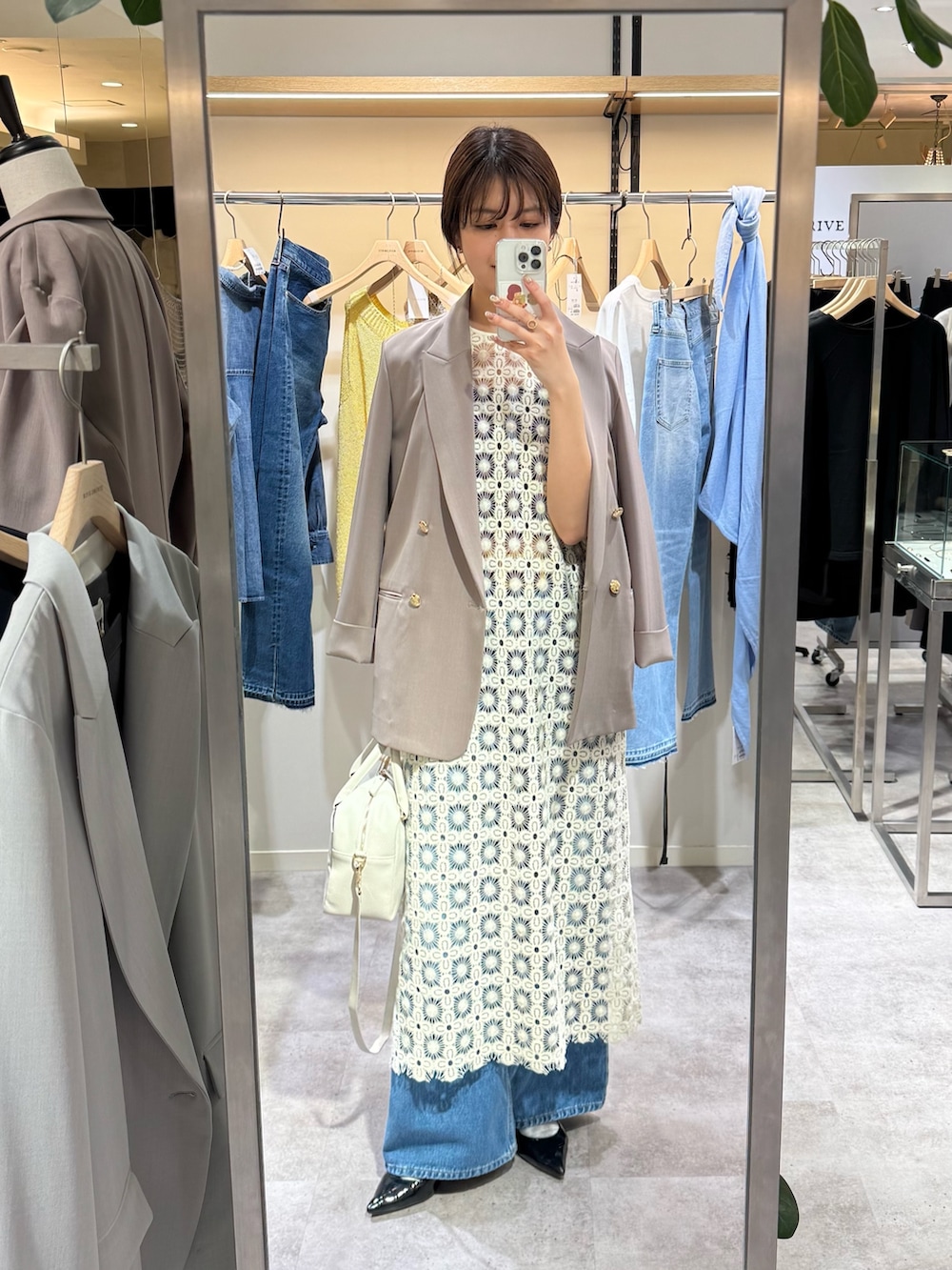 ブラウン系のテーラードジャケット、ホワイト系のワンピース、ブルー系のデニムパンツを着用したレディースの冬コーディネートの2枚目の写真