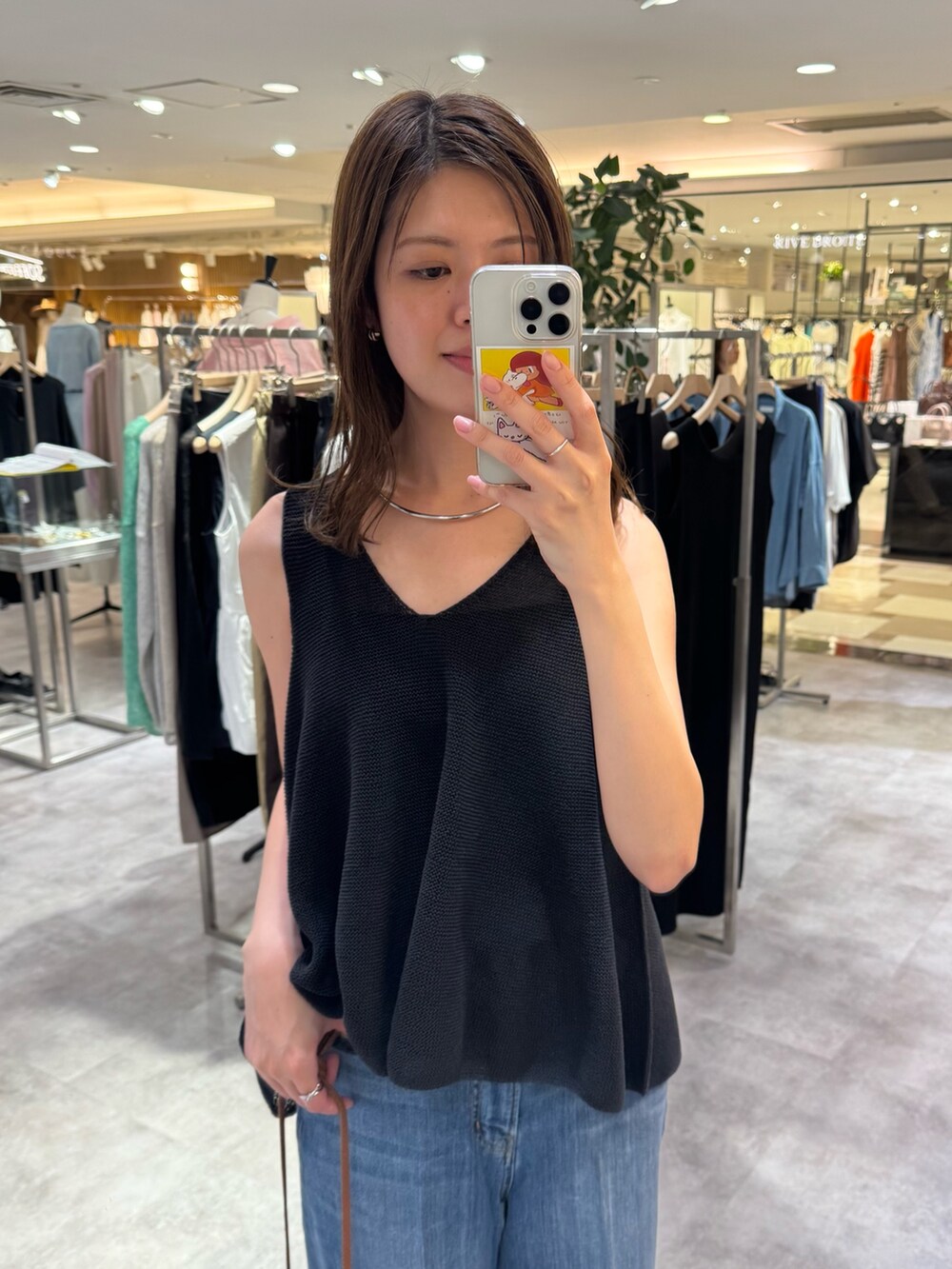 ブラック系のニット/セーター、ブルー系のデニムパンツ、ホワイト系のシャツ/ブラウスを着用したレディースの夏コーディネートの3枚目の写真