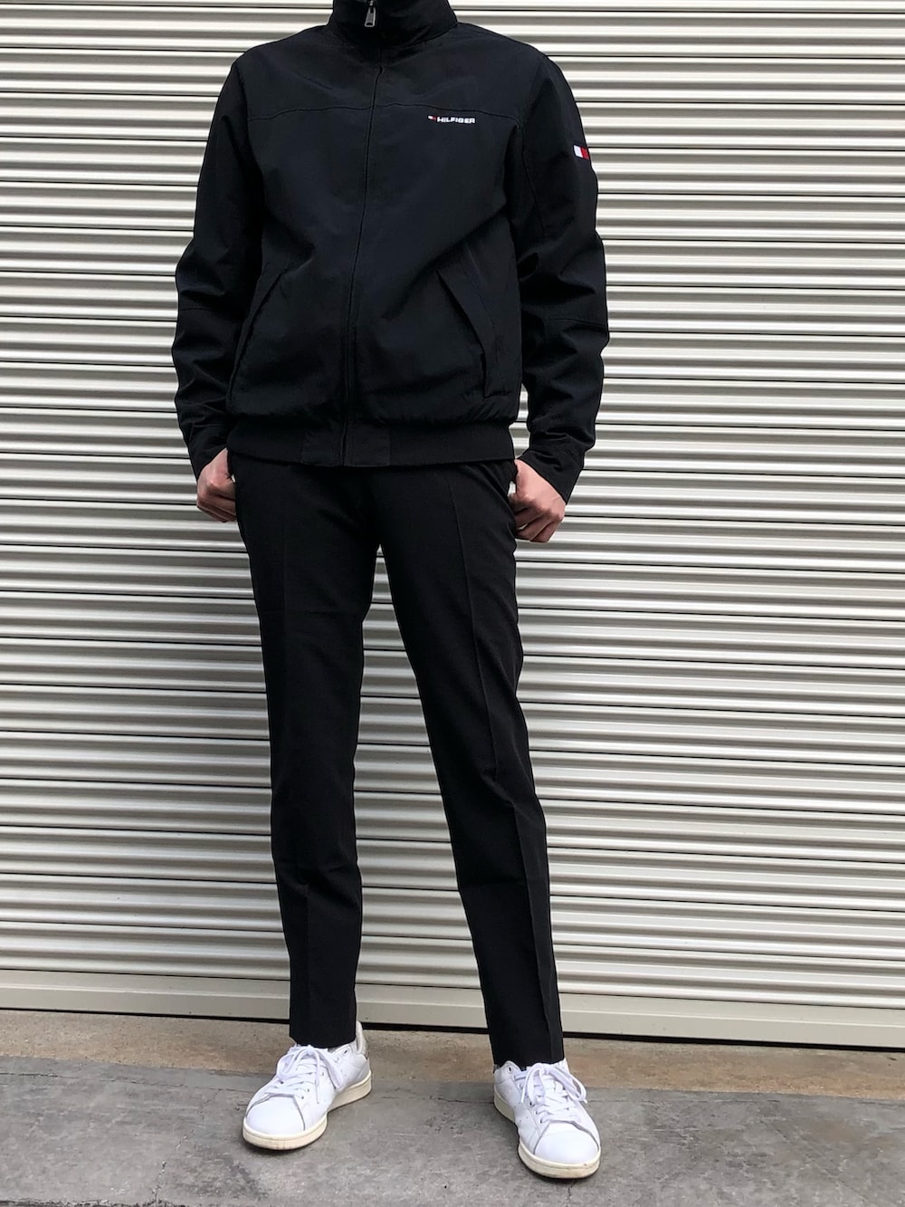 ブラック系のスラックス、ホワイト系のスニーカー、ブラック系のブルゾンを着用したメンズの冬コーディネートの2枚目の写真