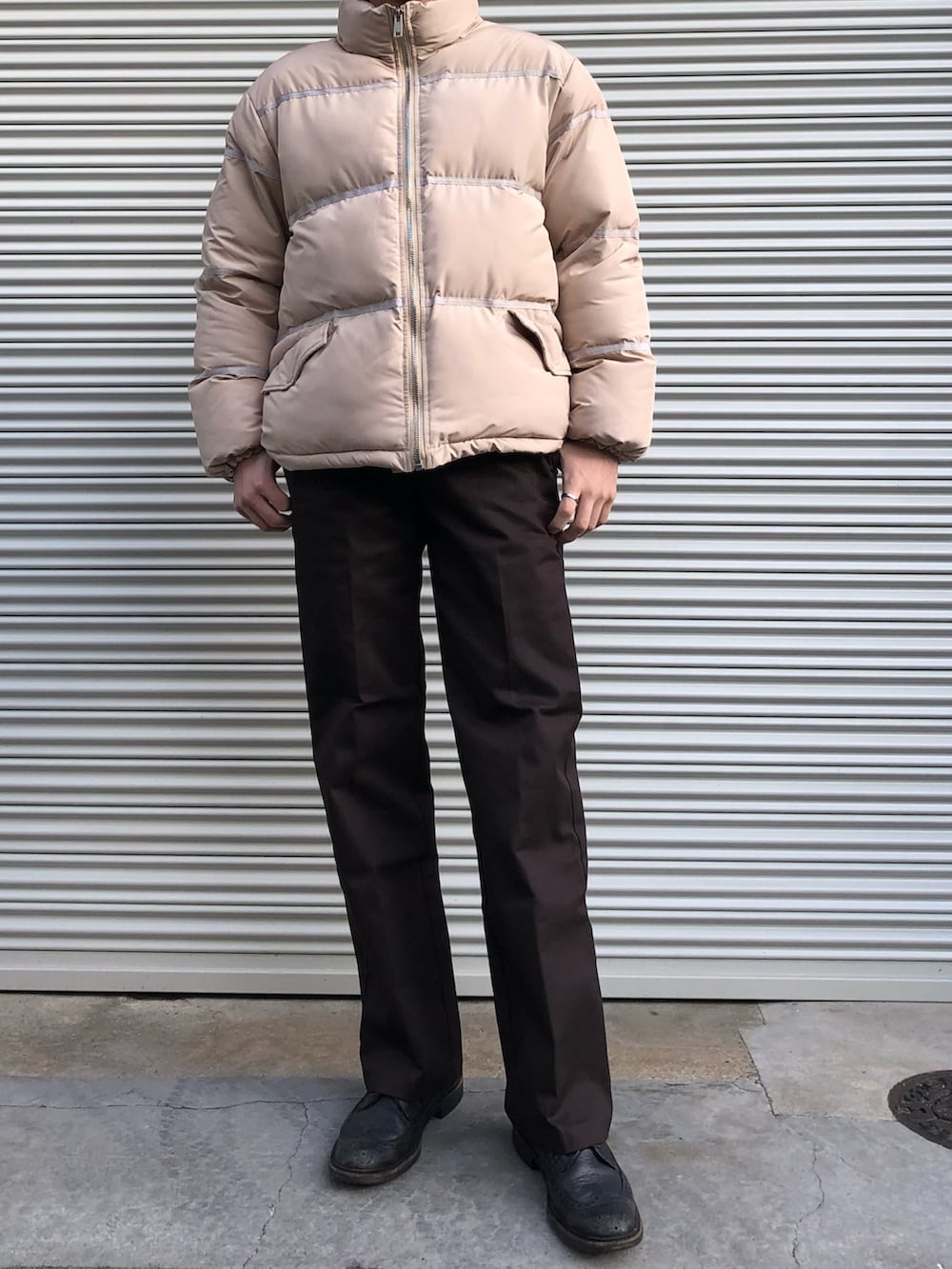 ブラウン系のチノパンツ、ブラック系のドレスシューズ、ベージュ系のダウンジャケット/コートを着用したメンズの冬コーディネートの2枚目の写真