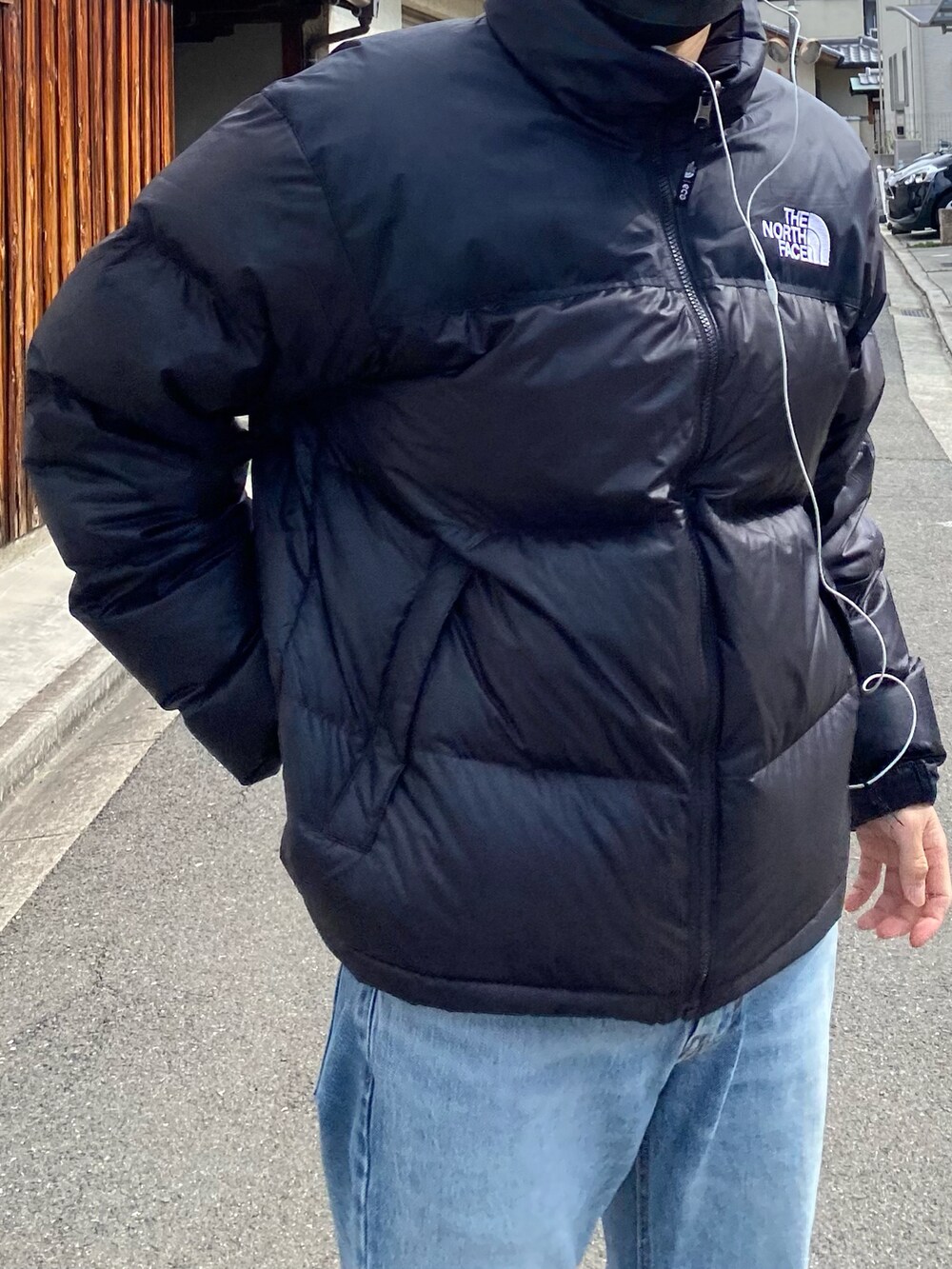 ブルー系のデニムパンツ、ブラック系のダウンジャケット/コートを着用したメンズの春コーディネートの2枚目の写真