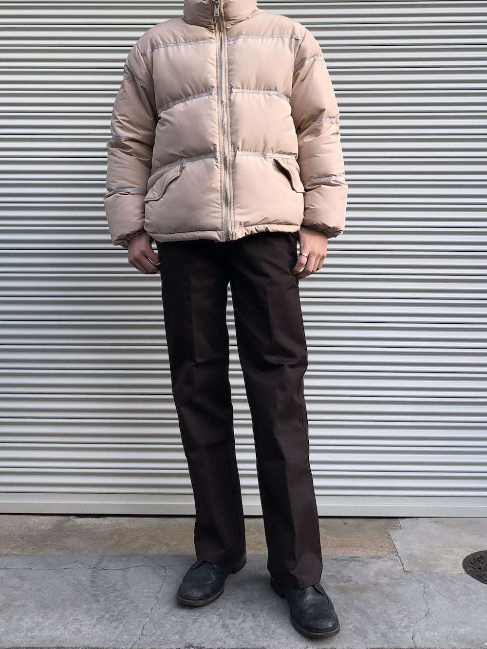 ブラウン系のチノパンツ、ブラック系のドレスシューズ、ベージュ系のダウンジャケット/コートを着用したメンズの冬コーディネートの3枚目の写真