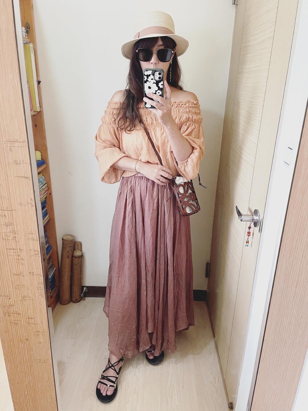 オレンジ系のトップス、ブラウン系のバッグ、ブラウン系のスカートを着用したレディースの夏コーディネートの2枚目の写真