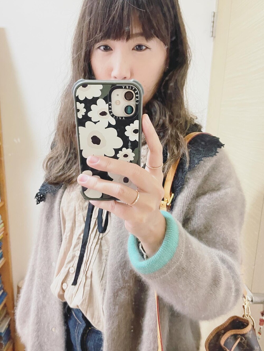 ベージュ系のカーディガン/ボレロ、ベージュ系のシャツ/ブラウス、ブラウン系のバッグを着用したレディースの冬コーディネートの2枚目の写真