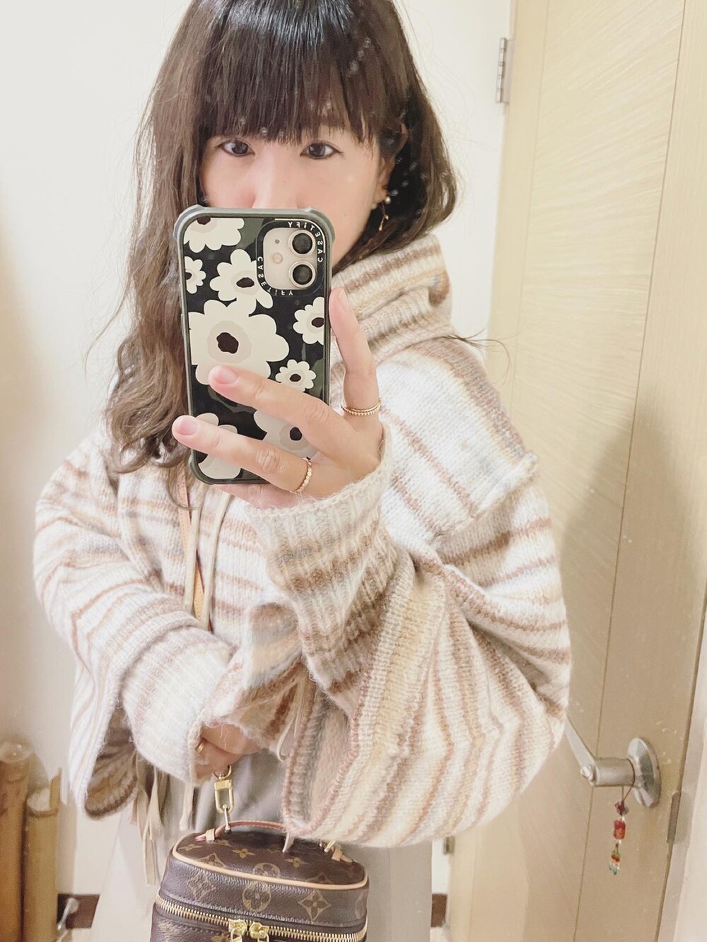 ベージュ系のニット/セーター、ブラウン系のバッグ、グリーン系のワンピースを着用したレディースの冬コーディネートの2枚目の写真