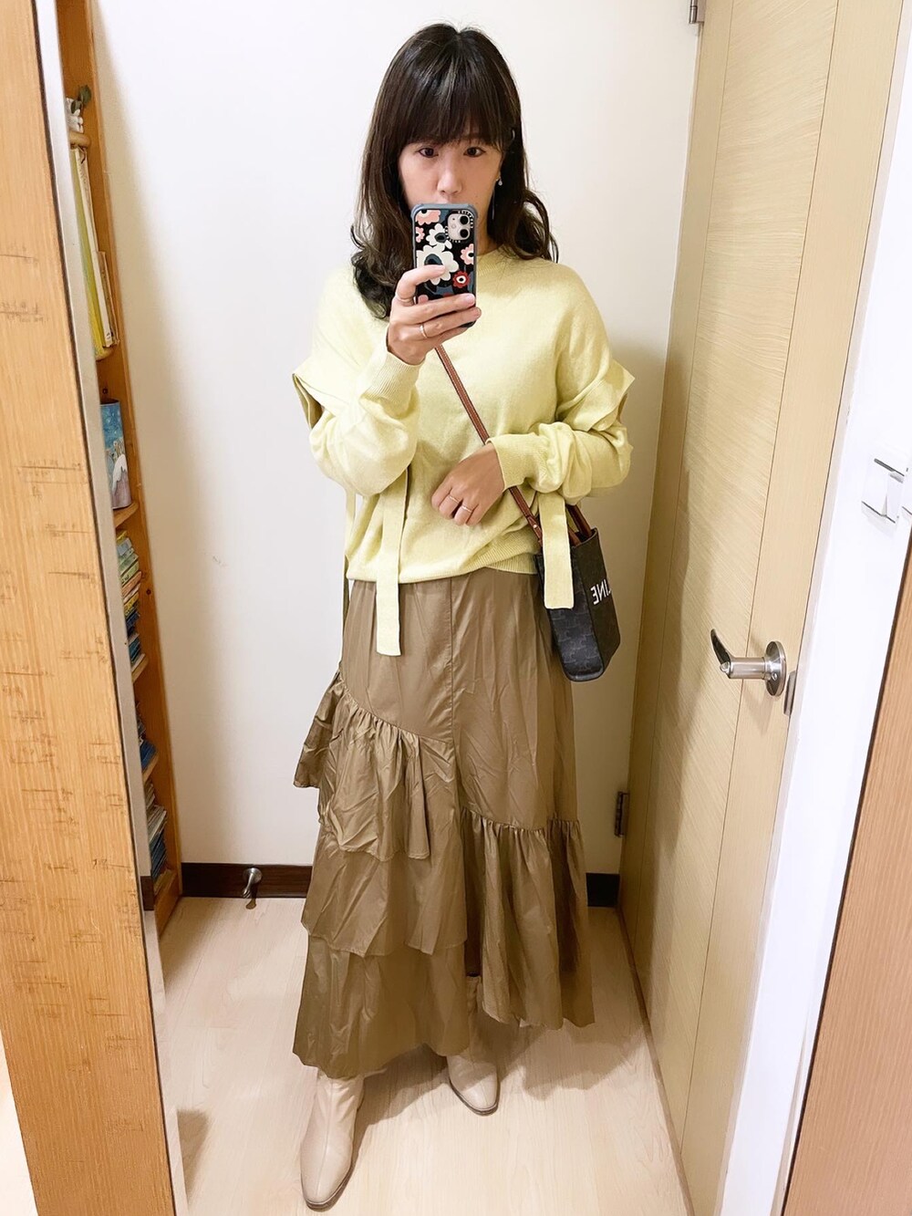 イエロー系のトップス、ベージュ系のスカート、ブラウン系のバッグを着用したレディースの冬コーディネートの2枚目の写真