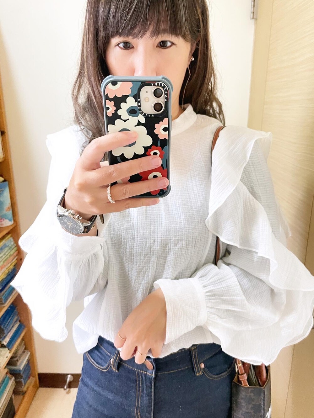 ブルー系のデニムパンツ、ブラウン系のバッグ、ホワイト系のトップスを着用したレディースの冬コーディネートの2枚目の写真