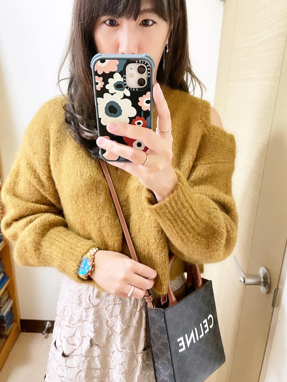 イエロー系のトップス、ベージュ系のスカート、ブラウン系のバッグを着用したレディースの冬コーディネートの2枚目の写真