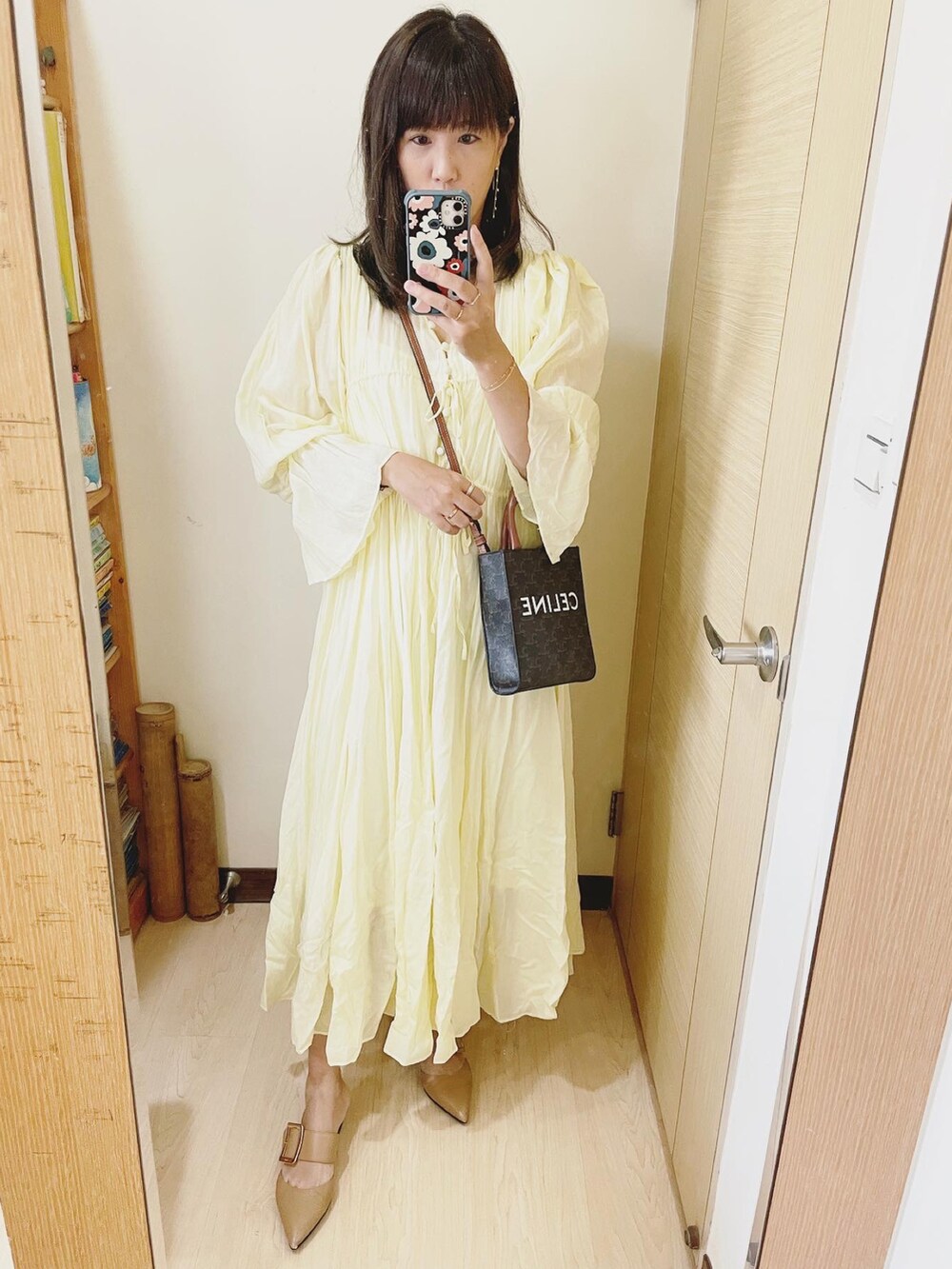 イエロー系のワンピース、ブラウン系のバッグ、ベージュ系のスリッポンを着用したレディースの秋コーディネートの2枚目の写真