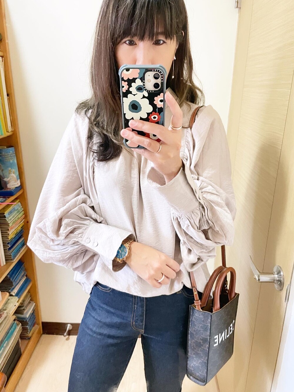 ブルー系のデニムパンツ、ブラウン系のバッグ、ベージュ系のシャツ/ブラウスを着用したレディースの冬コーディネートの2枚目の写真