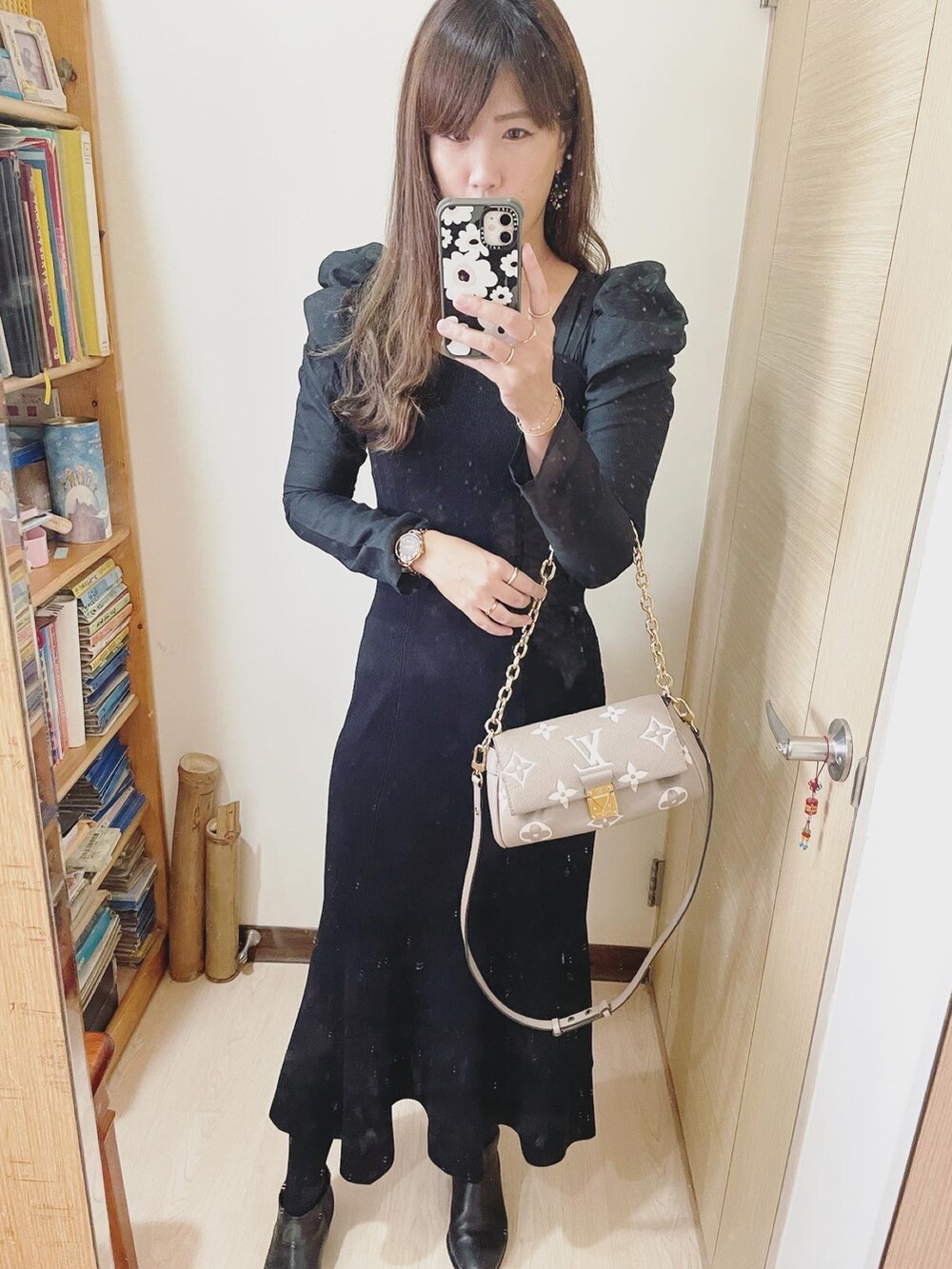 グレー系のバッグ、ブラック系のワンピース、ブラック系のブーツを着用したレディースの冬コーディネートの2枚目の写真