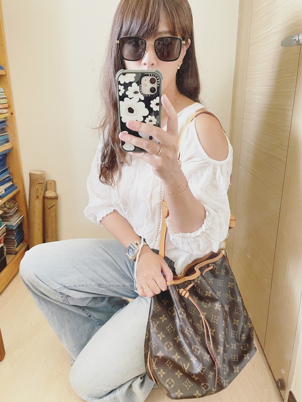 ブルー系のデニムパンツ、ブラウン系のバッグ、ホワイト系のシャツ/ブラウスを着用したレディースの夏コーディネートの3枚目の写真