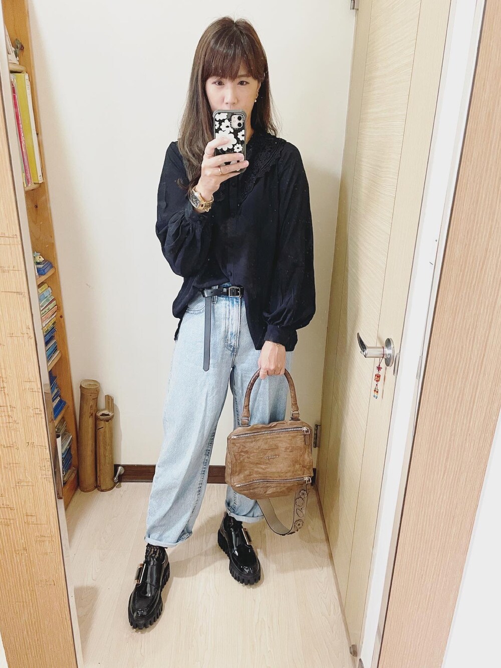 ブルー系のデニムパンツ、グレー系のショルダーバッグ、ブラック系のシャツ/ブラウスを着用したレディースの秋コーディネートの2枚目の写真