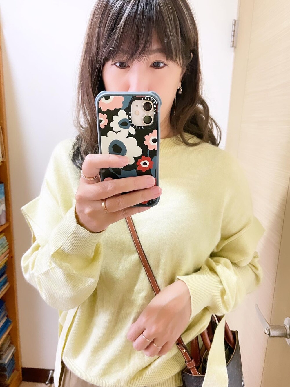 イエロー系のトップス、ベージュ系のスカート、ブラウン系のバッグを着用したレディースの冬コーディネートの3枚目の写真