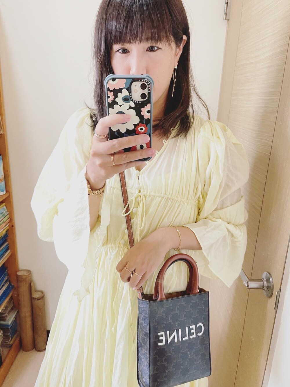 イエロー系のワンピース、ブラウン系のバッグ、ベージュ系のスリッポンを着用したレディースの秋コーディネートの3枚目の写真