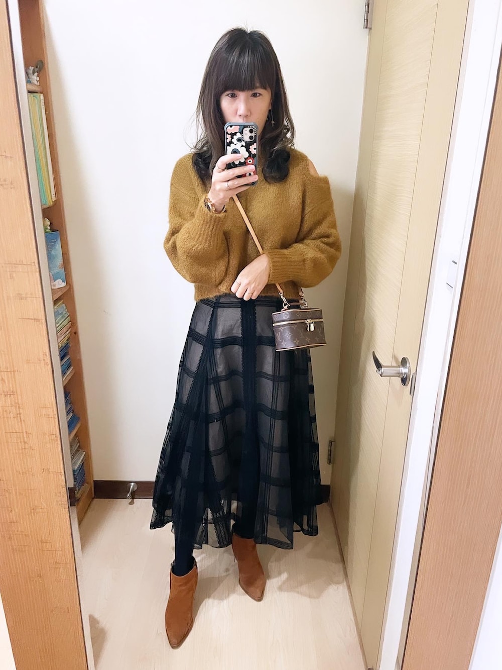 ブラック系のスカート、イエロー系のトップス、ブラウン系のバッグを着用したレディースの冬コーディネートの2枚目の写真