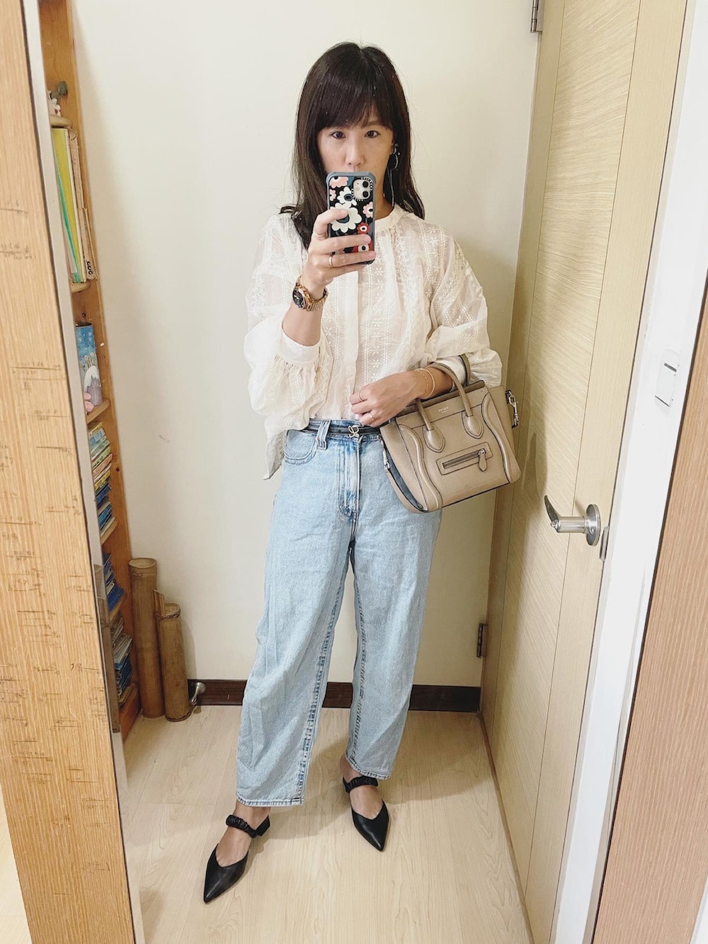 ブルー系のデニムパンツ、ホワイト系のシャツ/ブラウス、ベージュ系のバッグを着用したレディースの秋コーディネートの2枚目の写真