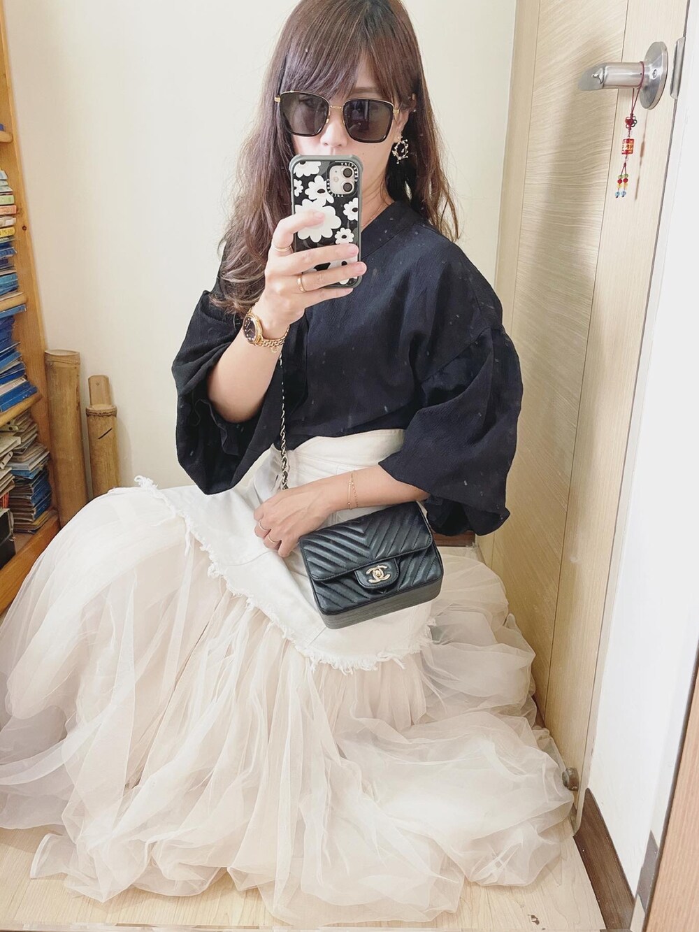 ブラック系のシャツ/ブラウス、ブラック系のバッグ、ホワイト系のデニムスカートを着用したレディースの春コーディネートの2枚目の写真