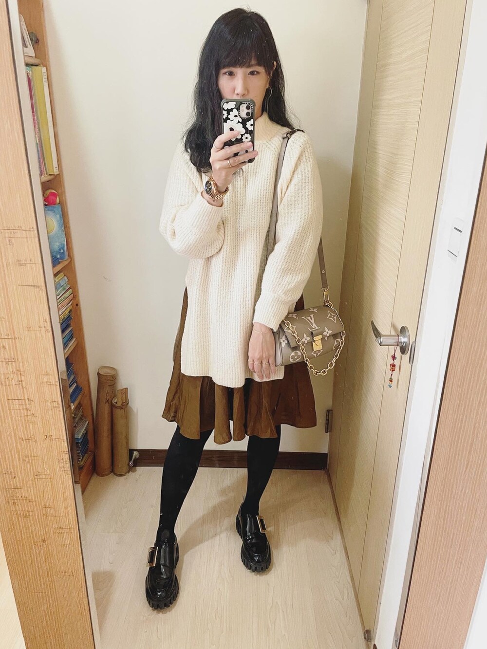 グレー系のバッグ、ホワイト系のニット/セーター、ブラウン系のワンピースを着用したレディースの冬コーディネートの2枚目の写真