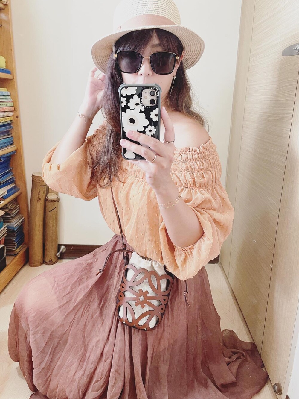 オレンジ系のトップス、ブラウン系のバッグ、ブラウン系のスカートを着用したレディースの夏コーディネートの3枚目の写真