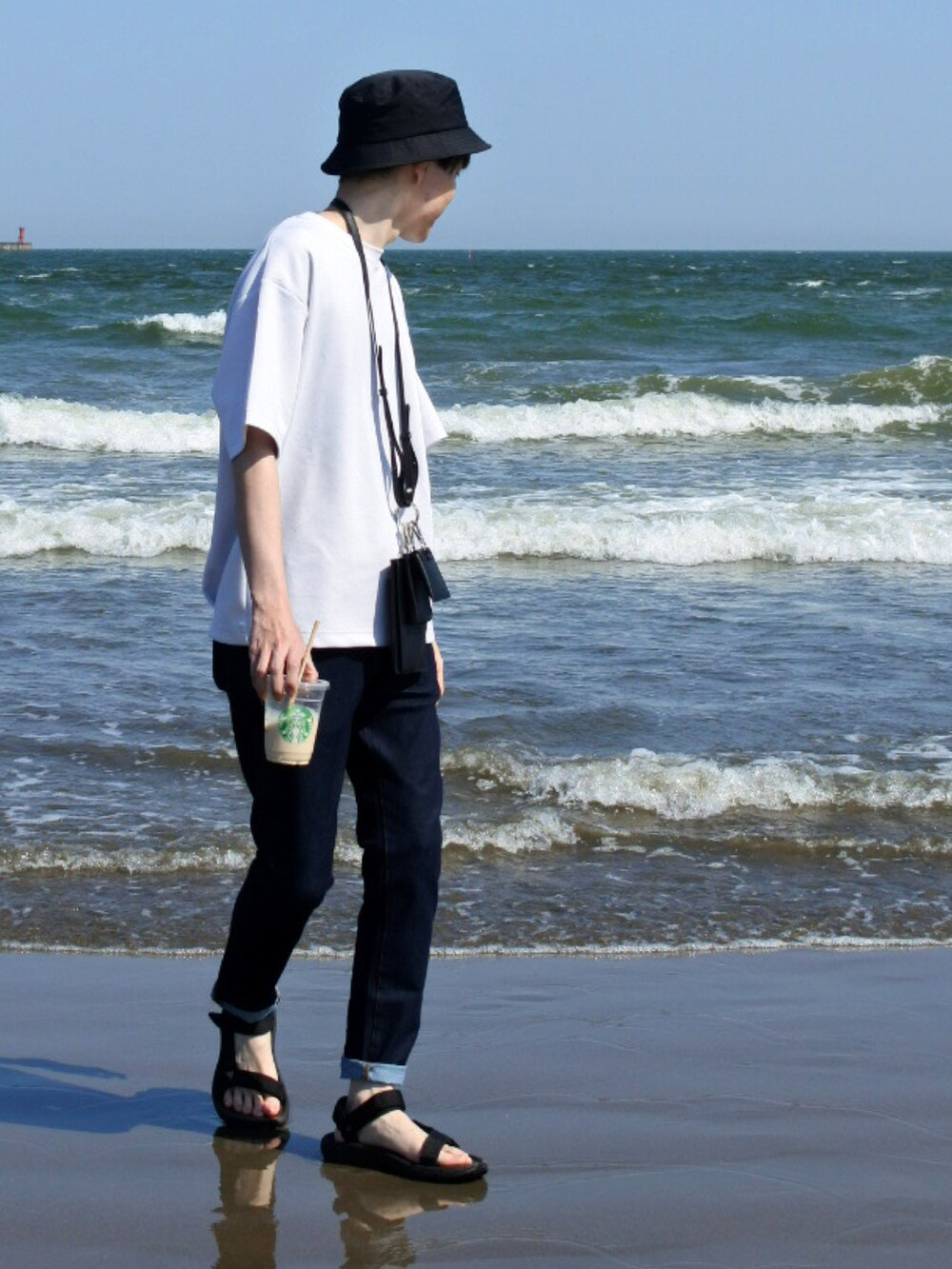 ホワイト系のTシャツ/カットソー、ブルー系のデニムパンツ、ブラック系のサンダルを着用したメンズの夏コーディネートの2枚目の写真