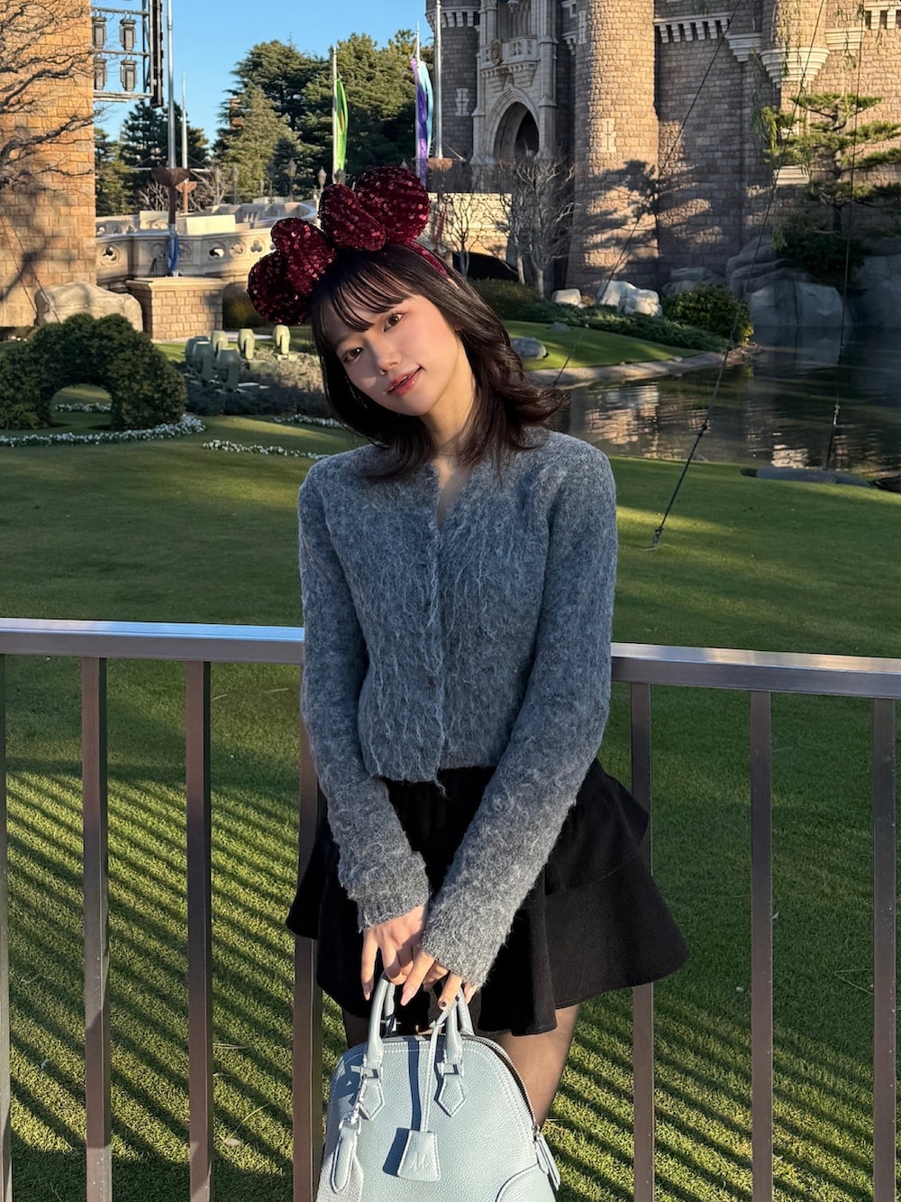 ブルー系のボストンバッグ、ブラウン系のブーツ、ブラック系のスカートを着用したレディースの冬コーディネートの2枚目の写真