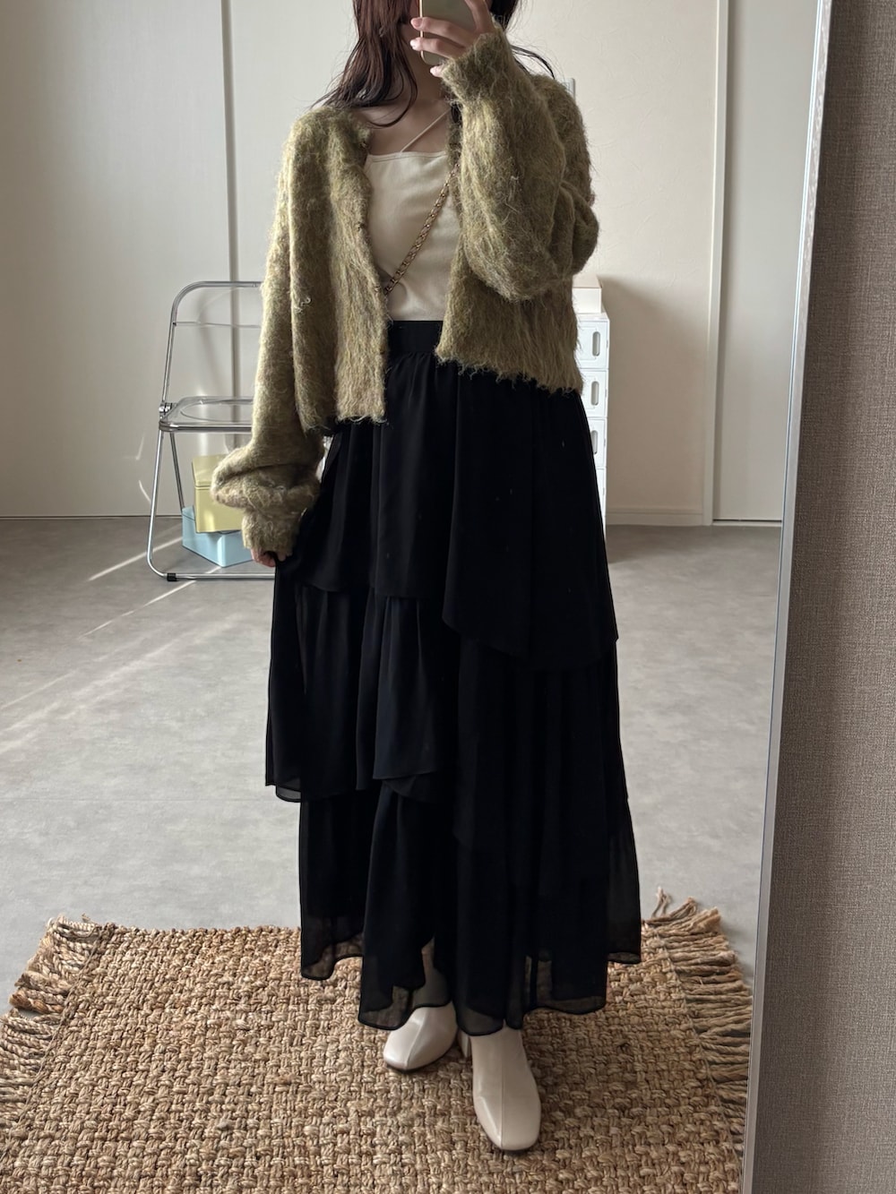 グリーン系のニット/セーター、ホワイト系のキャミソール、ブラック系のセットアップを着用したレディースの秋コーディネートの2枚目の写真