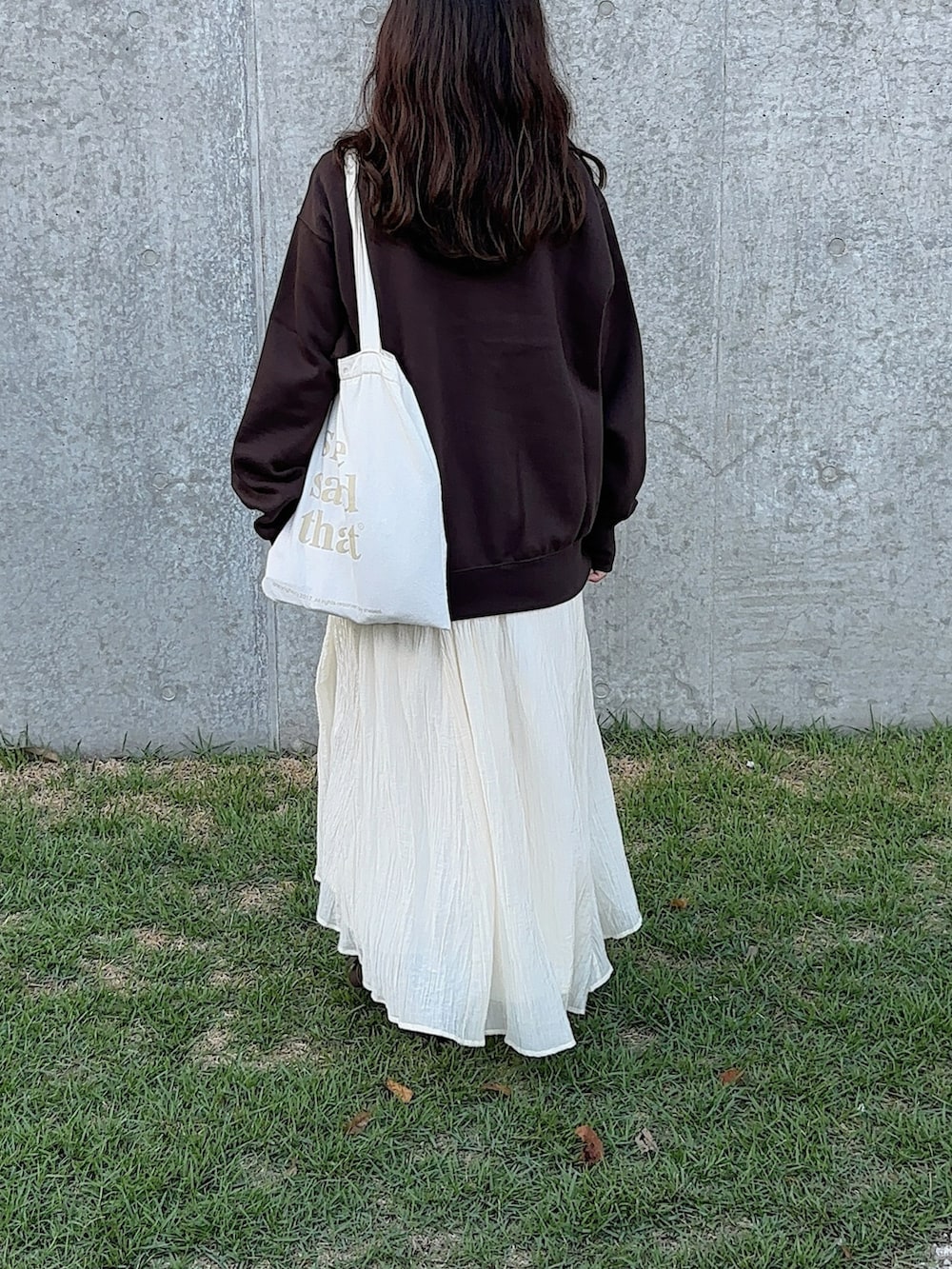 ブラウン系のスウェット、ホワイト系のトートバッグ、ホワイト系のワンピースを着用したレディースの秋コーディネートの2枚目の写真