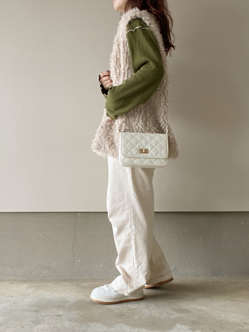 ベージュ系のベスト、グリーン系のニット/セーター、ベージュ系のデニムパンツを着用したレディースの秋コーディネートの2枚目の写真