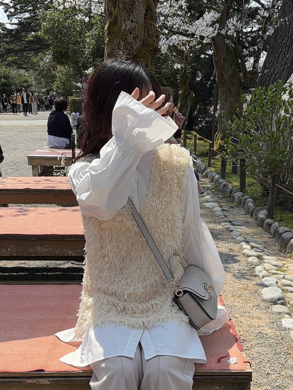 ホワイト系のベスト、ホワイト系のシャツ/ブラウス、ベージュ系のショルダーバッグを着用したレディースの春コーディネートの4枚目の写真