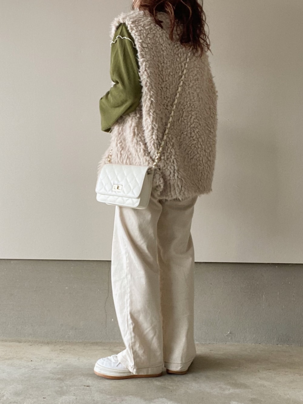 ベージュ系のベスト、グリーン系のニット/セーター、ベージュ系のデニムパンツを着用したレディースの秋コーディネートの3枚目の写真