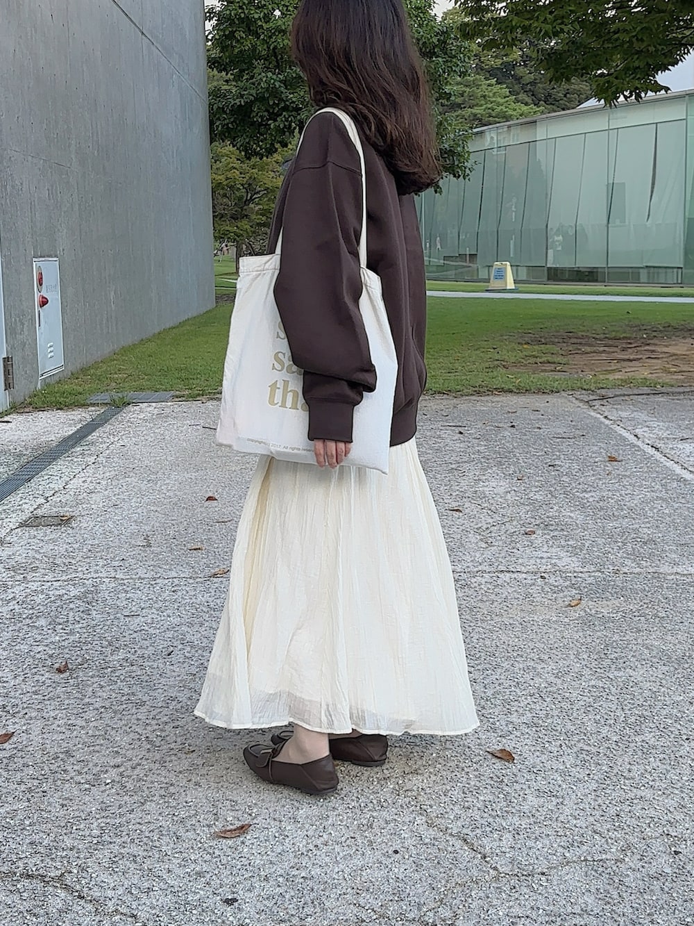 ブラウン系のスウェット、ホワイト系のトートバッグ、ホワイト系のワンピースを着用したレディースの秋コーディネートの3枚目の写真