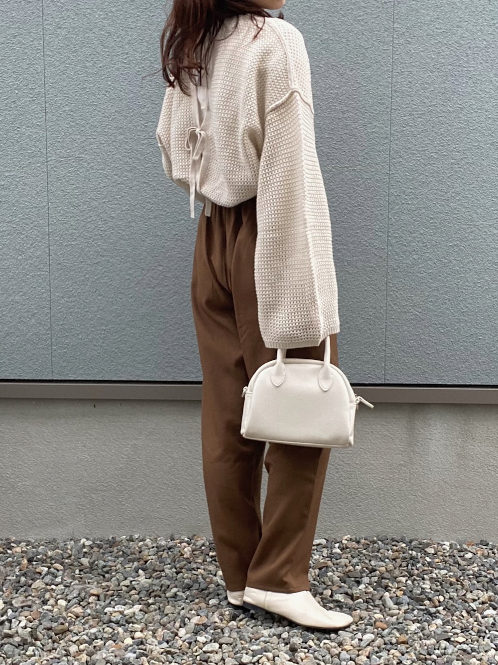 ベージュ系のニット/セーター、ホワイト系のハンドバッグ、ブラウン系のパンツを着用したレディースの冬コーディネートの2枚目の写真