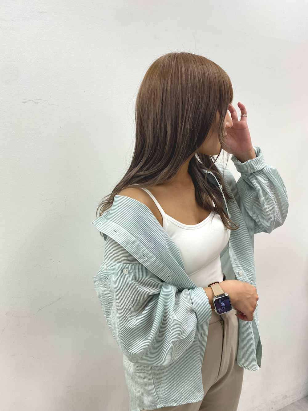 ベージュ系のスラックス、グリーン系のシャツ/ブラウス、ホワイト系のキャミソールを着用したレディースの春コーディネートの3枚目の写真