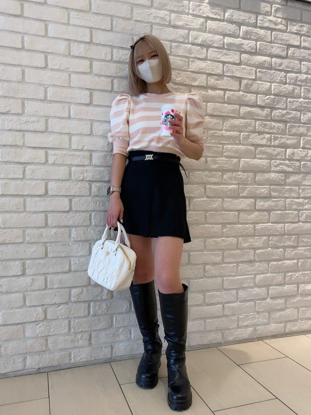 ピンク系のTシャツ/カットソー、ブラック系のスカート、ホワイト系のボストンバッグを着用したレディースの春コーディネートの3枚目の写真