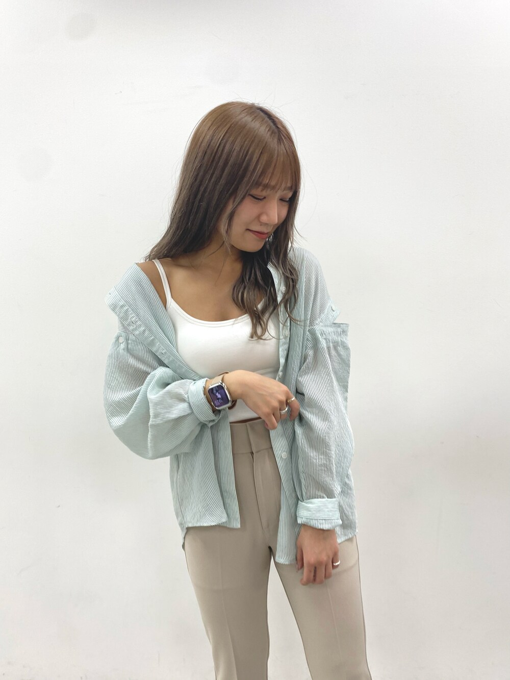 ベージュ系のスラックス、グリーン系のシャツ/ブラウス、ホワイト系のキャミソールを着用したレディースの春コーディネートの2枚目の写真