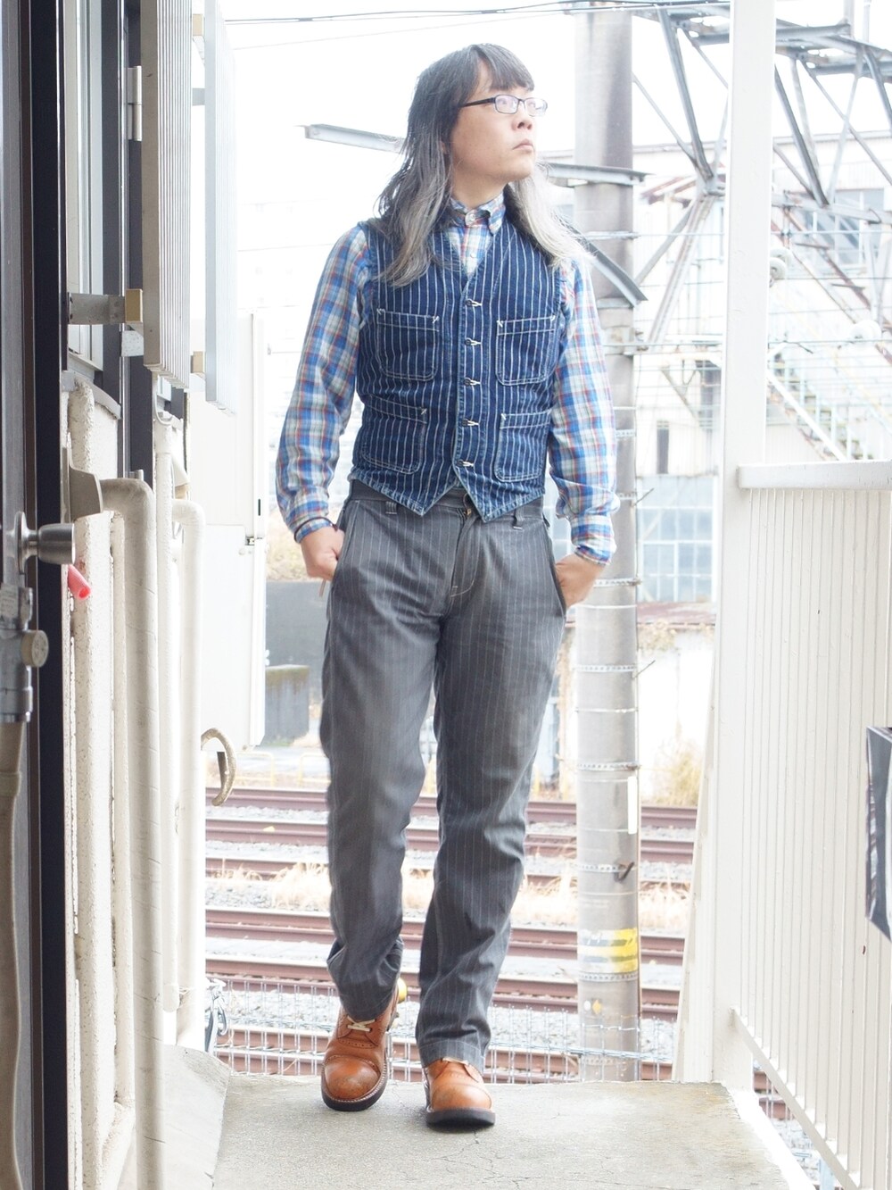 グレー系のチノパンツ、オレンジ系のブーツ、ブルー系のライダースジャケットを着用したメンズの冬コーディネートの2枚目の写真