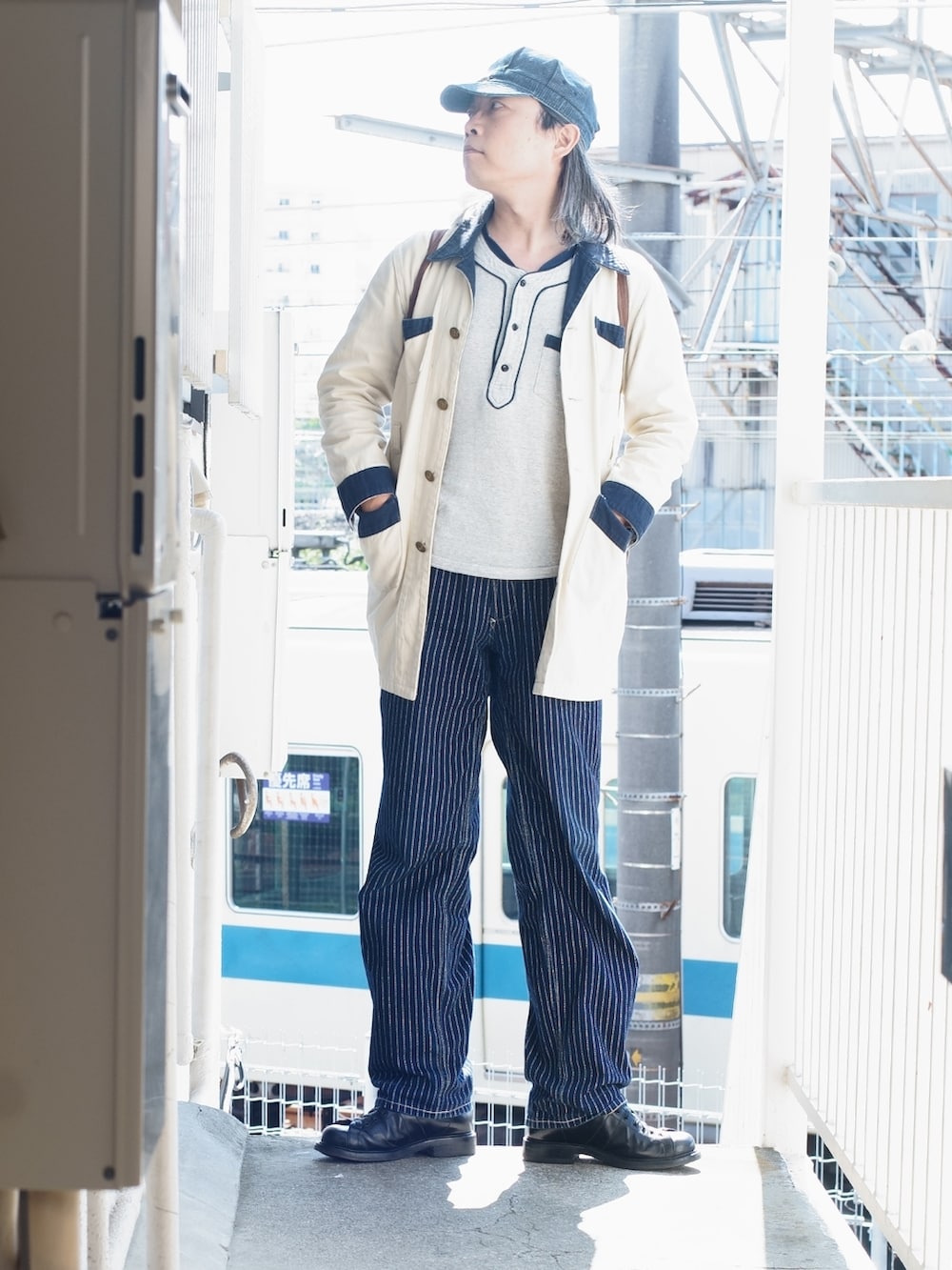 ブルー系のデニムパンツ、ブラック系のブーツ、ブルー系のキャップを着用したメンズの夏コーディネートの2枚目の写真