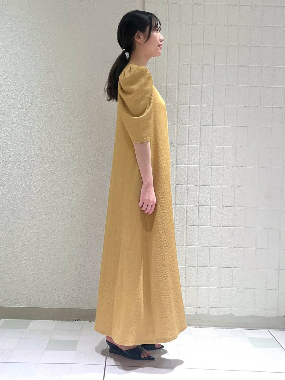 ブラック系のサンダル、ブラック系のショルダーバッグ、オレンジ系のワンピースを着用したレディースの夏コーディネートの2枚目の写真