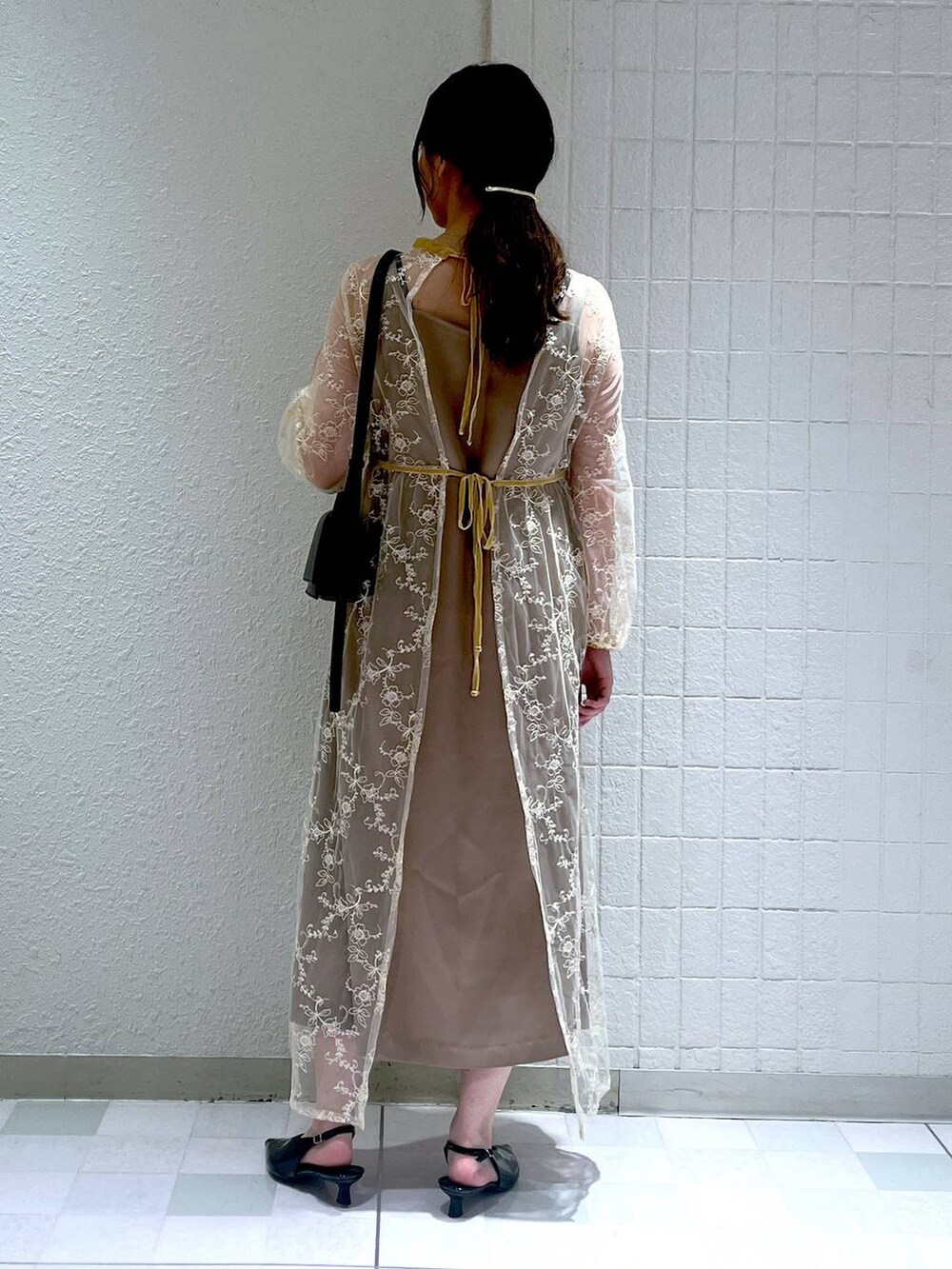 ブラック系のショルダーバッグ、ブラック系のパンプス、ベージュ系のドレスを着用したレディースの秋コーディネートの3枚目の写真