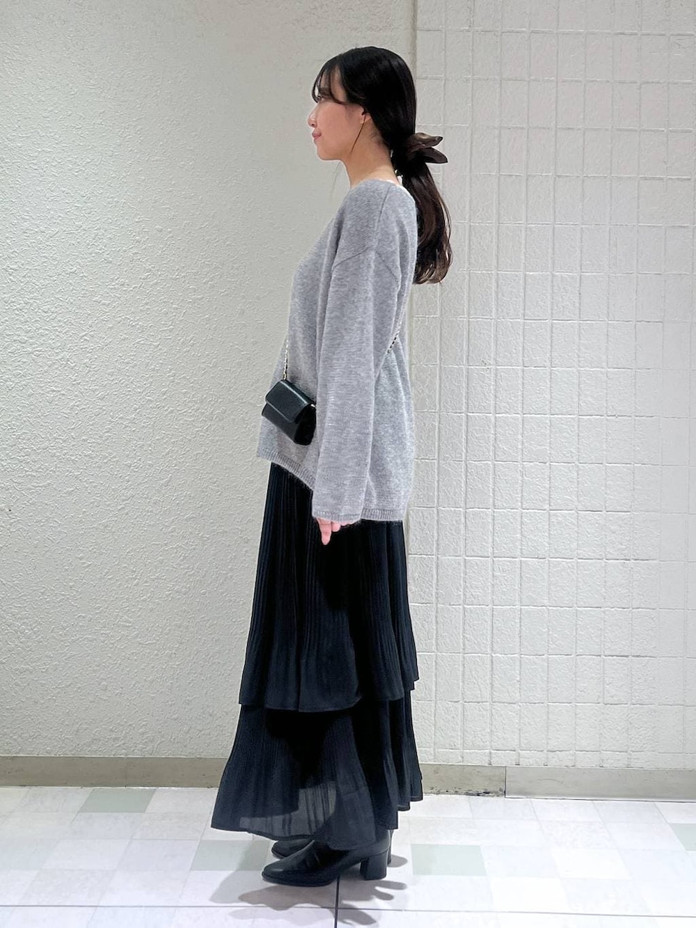 ブラック系のブーツ、ブラック系のスカート、グレー系のニット/セーターを着用したレディースの秋コーディネートの2枚目の写真
