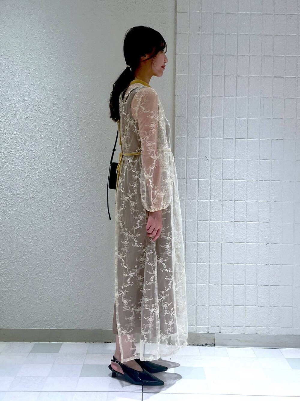 ブラック系のショルダーバッグ、ブラック系のパンプス、ベージュ系のドレスを着用したレディースの秋コーディネートの2枚目の写真