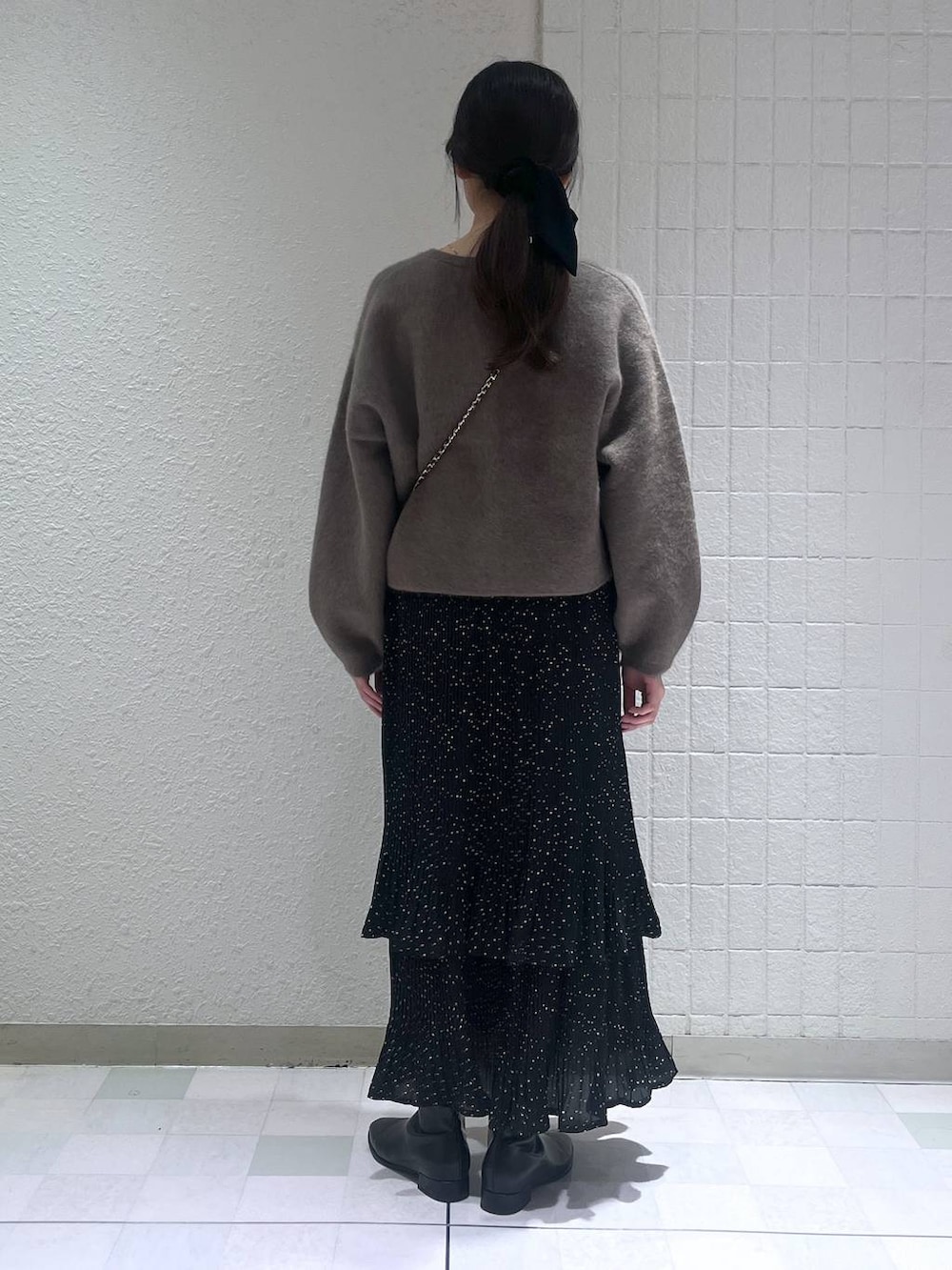 グレー系のスカート、ブラック系のブーツ、ゴールド系のネックレスを着用したレディースの秋コーディネートの3枚目の写真